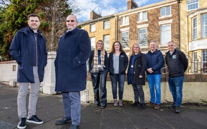 Representatives from Zenith Mechanical Services, Prosper, Tyne Housing, Keelman Homes, North Star Housing, Livin Housing, and Durham Aged Mineworkers’ Homes smiling outside a terraced property