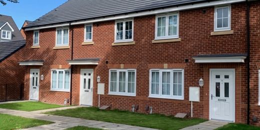Red brick terraced houses with white windows and doors and a small front garden.